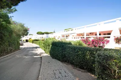 a street in front of a building with bushes and flowers at Large apartment in Vale do Lobo in Almancil