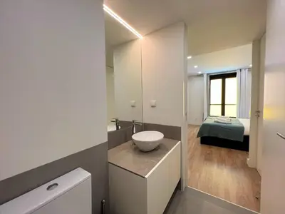 a bathroom with a sink and a toilet and a bed at Faro Design 4 by Homing in Faro