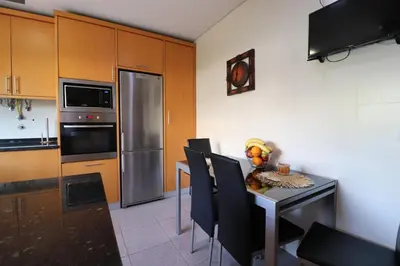 a kitchen with a table with chairs and a refrigerator at 3-Bed Townhouse with pool in Albufeira Balaia in Albufeira