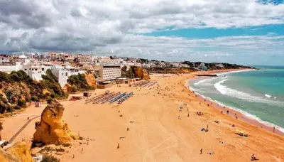 a beach with people on the sand and the ocean at In Downtown - Villa Serenity in Albufeira