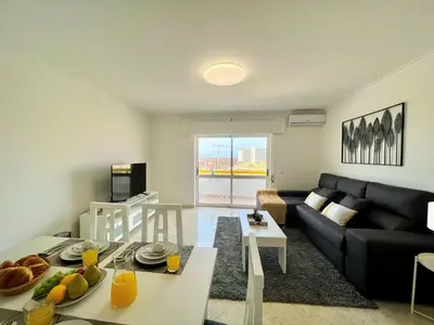 a living room with a couch and a table with food on it at Quarteira Panoramic View by Homing in Quarteira