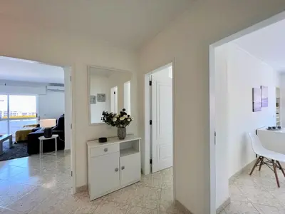 a living room with a table and a vase of flowers at Quarteira Panoramic View by Homing in Quarteira