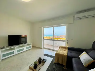 a living room with a couch and a flat screen tv at Quarteira Panoramic View by Homing in Quarteira