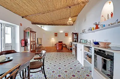 a kitchen with a table and chairs and a dining room at Casa Pedra São Romão in São Brás de Alportel