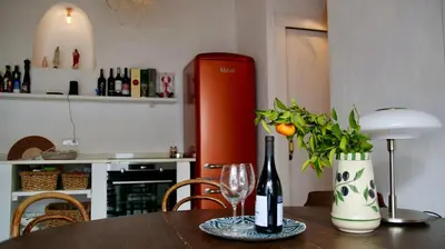a table with a wine glass and a red refrigerator at Casa Pedra São Romão in São Brás de Alportel