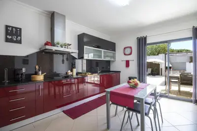 a kitchen with red cabinets and a table with chairs at Villa Maya in Almancil
