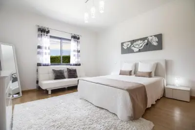 a white bedroom with a large bed and a couch at Villa Maya in Almancil