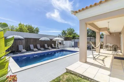 a pool with chairs and umbrellas in a backyard at Villa Maya in Almancil
