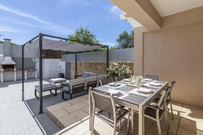 a patio with a table with chairs and an umbrella at Villa Maya in Almancil