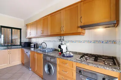 a kitchen with wooden cabinets and a stove top oven at Casa dos Salgados in Albufeira