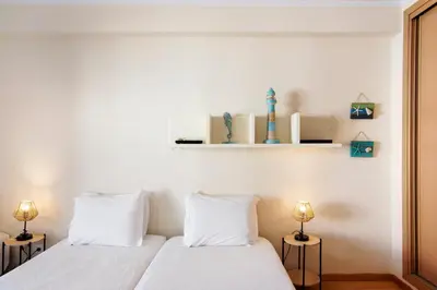 two beds in a room with white walls and two lamps at Casa dos Salgados in Albufeira
