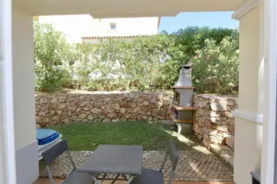 a patio with a table and chairs and a stone wall at Villa Bolivia-CleverDetails in Vilamoura