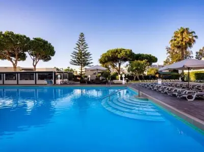 a large swimming pool with lounge chairs and trees at Albufeira Sol Villas III by Stay ici Algarve Holiday Rental in Albufeira