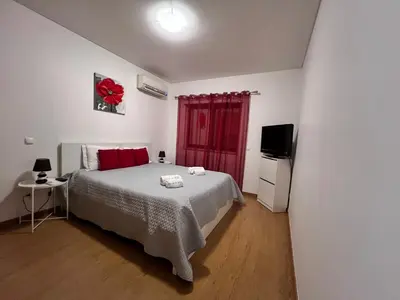 a bedroom with a bed and a tv in it at Mar e Sol by - T3 , wi-fi e estacionamento in Quarteira