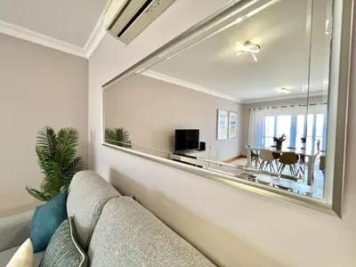 a living room with a couch and a large mirror at Victoria I - Vasco da Gama by HD PROPERTIES in Vilamoura