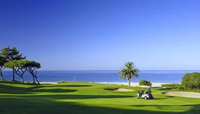 a golf cart on a green with the ocean in the background at Charming 2-Bed Apartment in Olhos de Agua in Albufeira