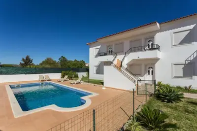 a villa with a swimming pool in front of a house at Beautiful 2-Bed Apartment in Olhos de Agua in Albufeira