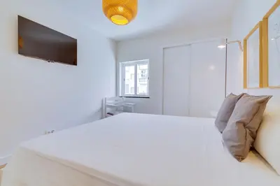a white bedroom with a large bed and a flat screen tv at AL - Apartamento Pontemira in Quarteira