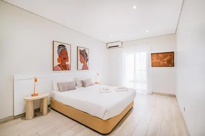a white bedroom with a bed and a table at Villa Kevin by Atlantic Places in Albufeira