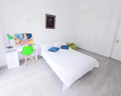 a bedroom with a bed and a desk with a green chair at Alojamento local 