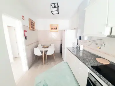 a small kitchen with a table and white cabinets at Alojamento local 