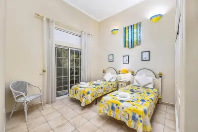 a bedroom with two beds and a chair at Villa Casa Sophia by Villa Plus in Olhos de Água