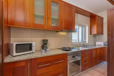 a kitchen with wooden cabinets and a microwave at Villa Casa Grande by Villa Plus in Albufeira