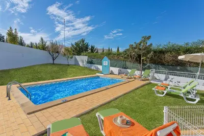 a swimming pool in a yard with lawn chairs and a pool at Villa Leonor by Villa Plus in Olhos de Água