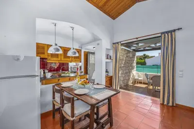 a kitchen and dining room with a table and a refrigerator at Villa Sunshine by Villa Plus in Albufeira