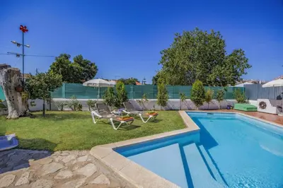 a swimming pool with two lawn chairs and a table at Villa Sunshine by Villa Plus in Albufeira