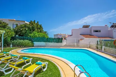 a swimming pool with lounge chairs next to a house at Villa Verao Sol by Villa Plus in Albufeira