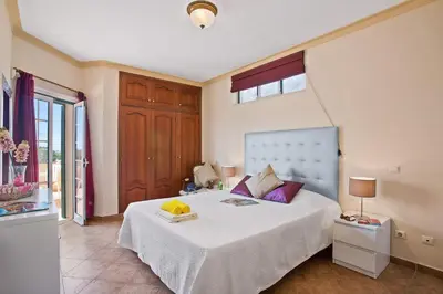 a bedroom with a large white bed with purple pillows at Villa Boavista by Villa Plus in Boliqueime