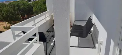 a balcony with two black chairs on the side of a house at Apartamento 90m2 com vista mar - Albufeira in Albufeira