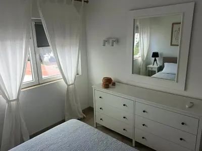 a white bedroom with a dresser and a mirror at Apartamento 90m2 com vista mar - Albufeira in Albufeira