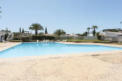 a large swimming pool with chairs and palm trees at Aldeia do Golfe - Private condominium by HD in Vilamoura