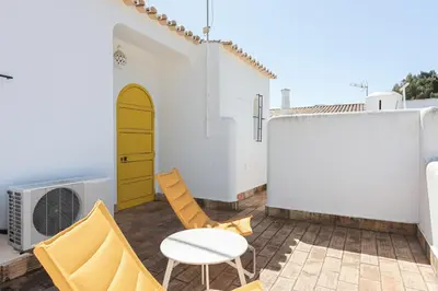a patio with chairs and a table and a yellow door at Aldeia do Golfe - Private condominium by HD in Vilamoura