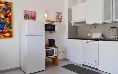 a kitchen with white cabinets and a microwave at BeGuest Feliz Choro Apartment in Branqueira