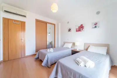 two beds in a room with white walls and wooden floors at Solário de São José - AD by HelloVacations in Albufeira