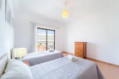 a white bedroom with two beds and a window at Solário de São José - AD by HelloVacations in Albufeira