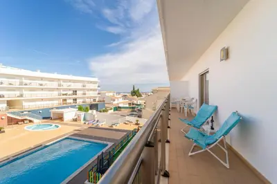 a balcony with a swimming pool and blue chairs at Solário de São José - AD by HelloVacations in Albufeira