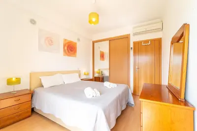 a bedroom with a white bed with a dresser and a mirror at Solário de São José - AD by HelloVacations in Albufeira