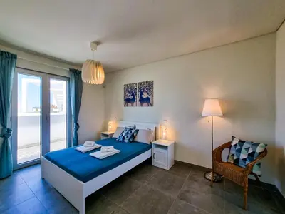 a bedroom with a blue bed and a window at FLH Vilamoura Duplex with Terrace & Pool in Vilamoura
