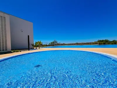 a large blue swimming pool next to a building at FLH Vilamoura Duplex with Terrace & Pool in Vilamoura