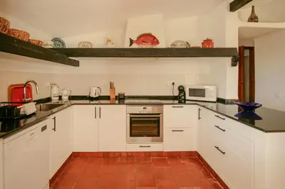 a kitchen with white cabinets and a red tile floor at FLH Balaia House with Terrace in Albufeira