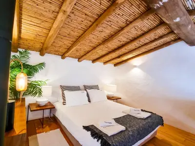 a bedroom with a white bed and a wooden ceiling at FLH Vale Judeu Rustic Mezzanine Cottage II in Loulé