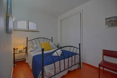 a bedroom with a bed with blue sheets and a yellow pillow at Apartamento Olhos D'Água VistaBella in Olhos de Água