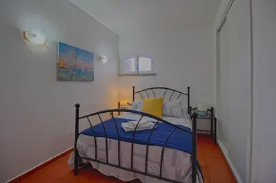 a bedroom with a bed with blue sheets and yellow pillows at Apartamento Olhos D'Água VistaBella in Olhos de Água