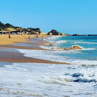 a beach with people walking on the sand and the water at New Appartment! Albufeira in Albufeira