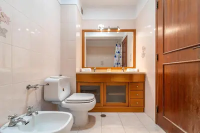 a bathroom with a toilet and a sink and a mirror at Quarteira Beach - 2 D by HelloVacations in Loulé