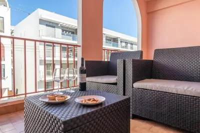 a bottle of wine sitting on a table on a balcony at Quarteira Beach - 2 D by HelloVacations in Loulé